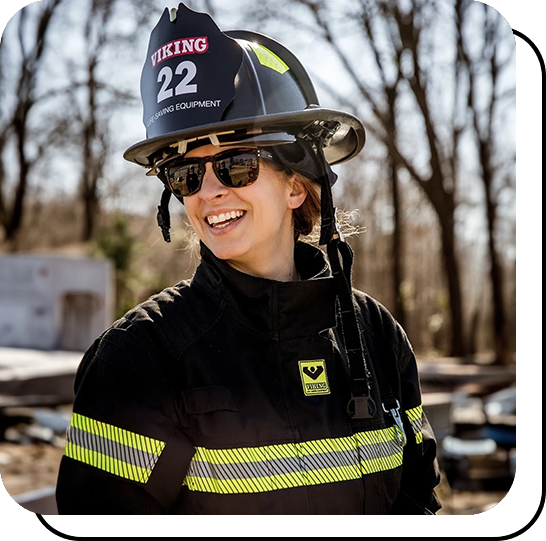 A woman in black jacket and helmet standing next to trees.